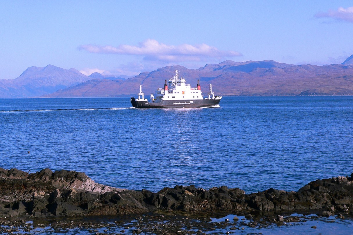 A ferry in the sea heading towards the Isle of Skye with mountains in the background