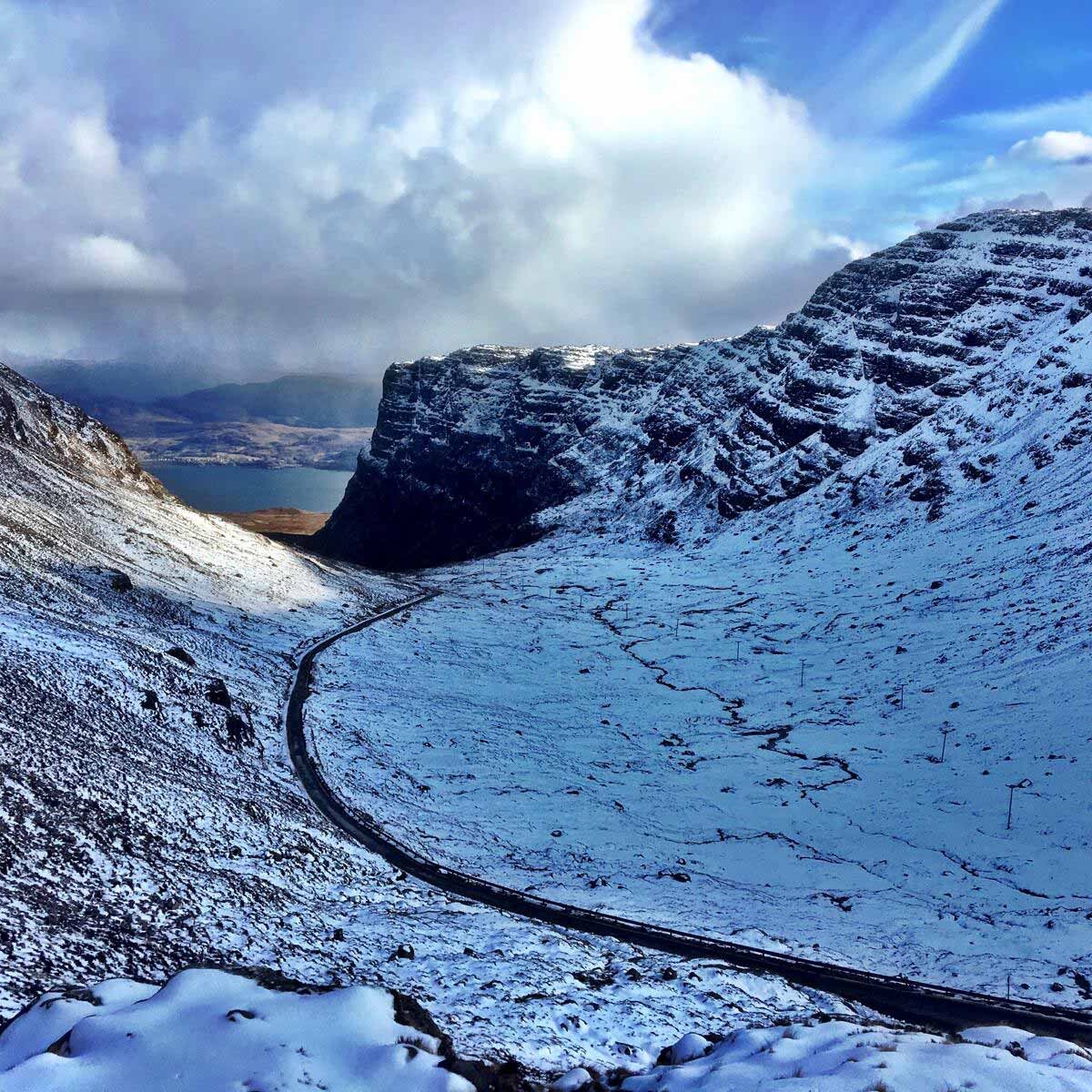 The Bealach na B&agrave; road on the North Coast 500 in Winter, surrounded by snow.
