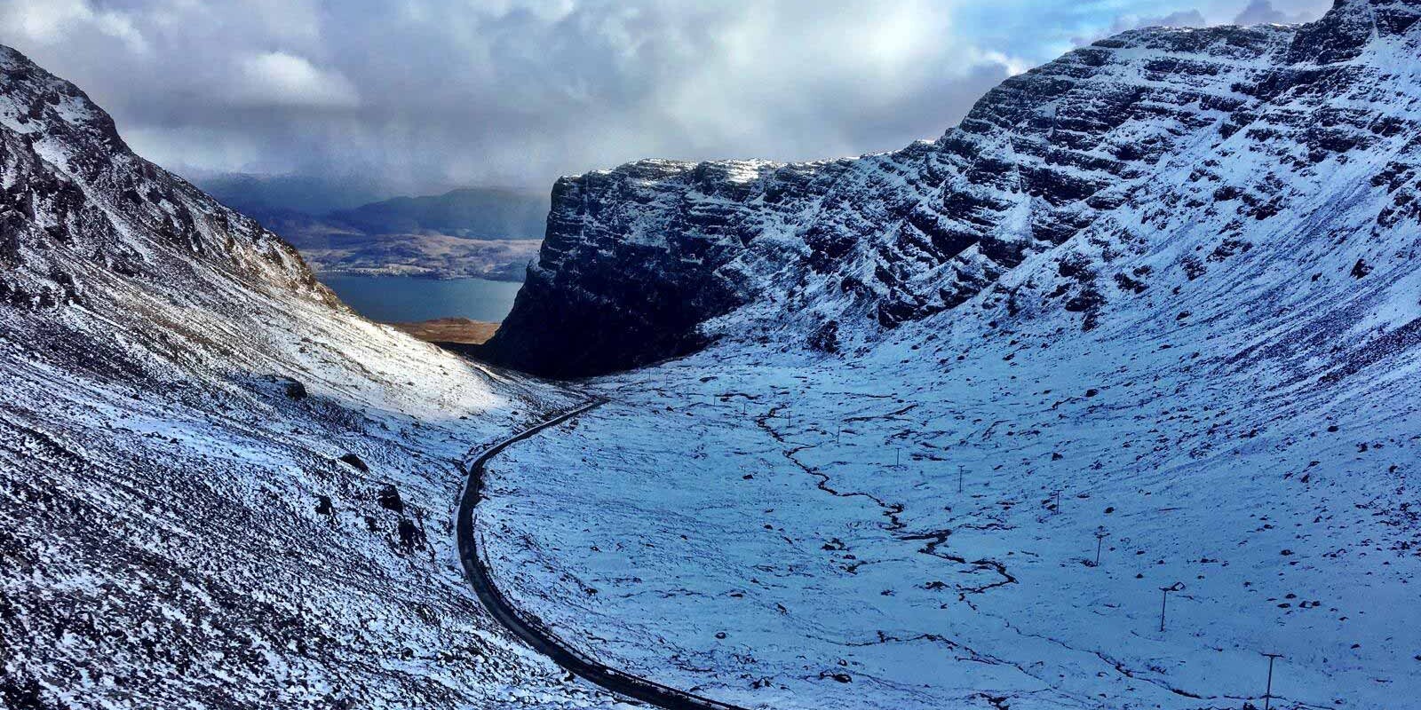 The Bealach na B&agrave; road on the North Coast 500 in Winter, surrounded by snow.